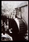 Man beside a water wheel. Black and white photo. 